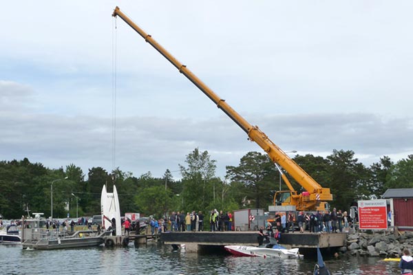 Mobilkran lyfter upp båt ur vatten